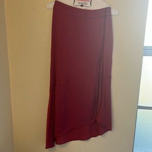 Asymmetrical skirt with a side slit up to thigh area. Red wine color